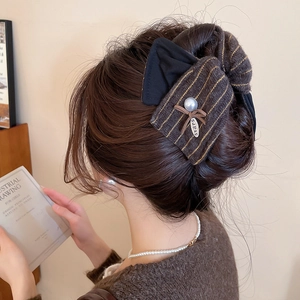Détail de la pince à cheveux noeud rayé marron avec perle et pendentif étoile