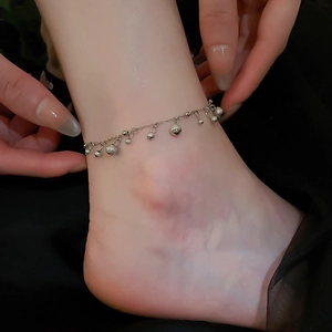 Détail d'une chevillère en argent avec breloques de fleurs en zircon sur la cheville