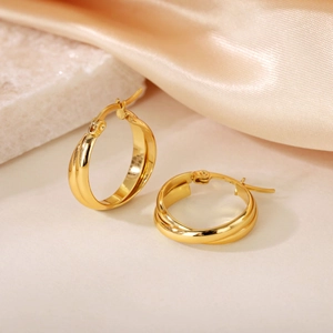 Detail of 18K gold-plated interlocking geometric double hoop earrings on silk background