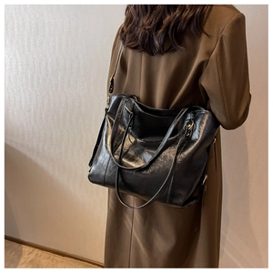 Detailed view of black polished leather tote bag on model for school and commute use