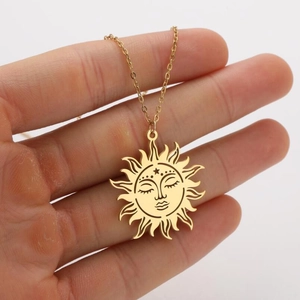 Detail of hand-held gold celestial sun face pendant with hollowed-out star design