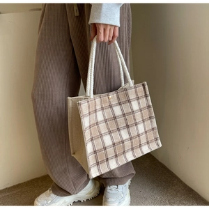 Detail of canvas tote bag with beige brown plaid pattern and white rope handles