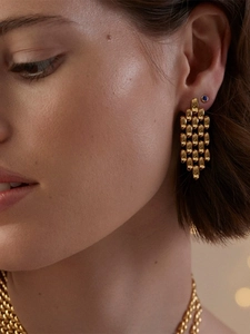 Close-up of golden woven chain earrings on model with soft lighting and elegant jewelry