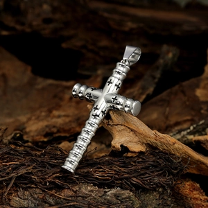 Macro detail of silver cross pendant with bamboo texture on a rustic wooden background