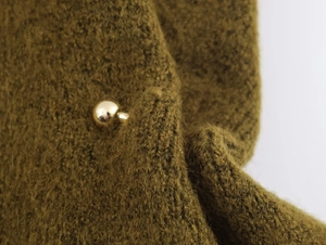 Macro detail of olive green mohair knit texture featuring a polished gold ball button