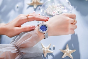 Detail of luxury rhinestone bezel watch with blue mother of pearl dial on silver mesh strap