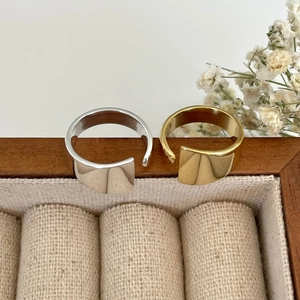 Minimalist wide open-style rings in gold and silver finish on a wooden box