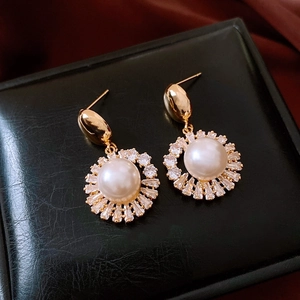 Close-up of vintage pearl earrings with gold plating and sparkling zircon halos
