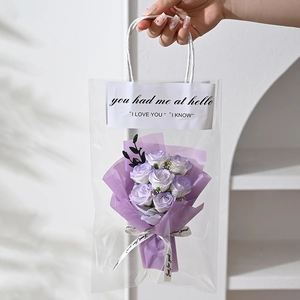 Detail of purple soap rose bouquet in a transparent carrier bag with decorative ribbons
