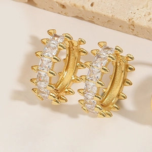 Detailed macro view of gold hoop earrings featuring rectangular zircons and metal spikes