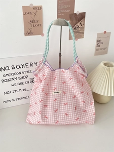 Detail of a pink checkered tote bag featuring ribbon prints and a purple bound top edge