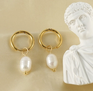 Dettaglio di orecchini a cerchio dorati con perle barocche su raso beige