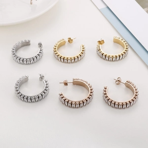 Detail of C-shaped hoop earrings with baguette-cut white zircons in gold and silver