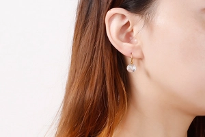 Close-up of golden titanium steel drop earrings with faceted clear crystal glass beads