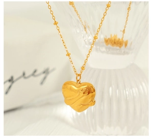Macro view of a 18K gold-plated heart pendant necklace on a clear glass background