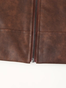 Détail de la fermeture éclair métallique et des coutures sur une veste en similicuir marron