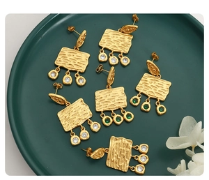 Close-up of vintage hammered gold earrings with cubic zirconia and wood grain texture