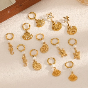 Golden ocean theme earring set featuring sea shells, starfish and pearls on a textured surface