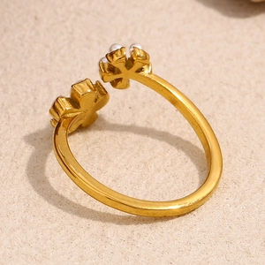 Detailed top view of 18K gold plated flower ring with elegant pearl accents on beige background