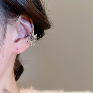 Close-up of silver flower ear cuffs with zircon crystals worn on a model's ear cartilage