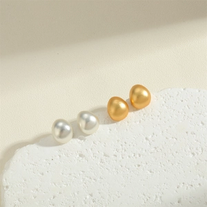 Minimalist geometric waterdrop earrings in matte gold and pearl white on stone pedestal