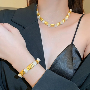 Vintage gold pearl flower necklace and bracelet set worn on a model in black attire