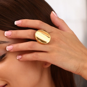 Macro shot of a large oval-shaped 18K gold-plated stainless steel ring on model's finger