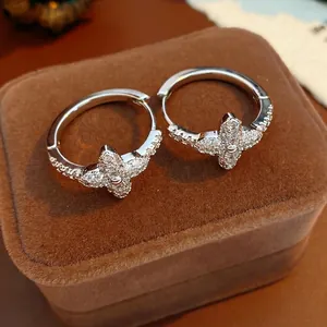 Elegant silver four-leaf clover hoop earrings with sparkling cubic zirconia on a velvet box