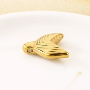 Detailed macro view of 18k gold-plated mermaid tail pendant accessory on ceramic