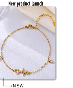 Macro detail of heartbeat and heart charms with zircon on golden stainless steel anklet