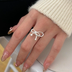 Detail of 925 sterling silver bow ring with hanging bead on model's finger