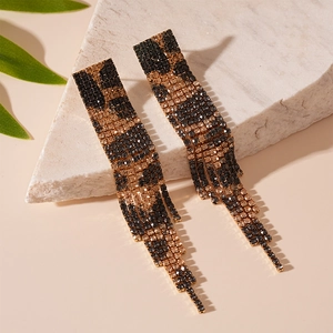 Macro detail of rectangle leopard print rhinestone fringe earrings on stone background