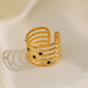 Hammered gold multi-layer open ring with five black dots on beige silk background