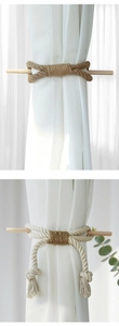 Detail of woven cotton curtain tieback with wooden rod and fringe in Nordic style
