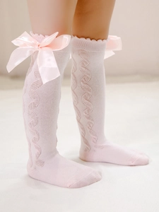 Close-up of pink knit baby socks with cable pattern and large satin bow detail