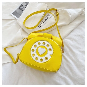 Detail of creative yellow patent leather crossbody bag in vintage telephone design with dial