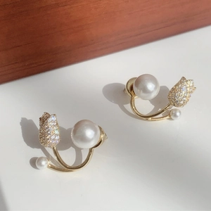 Detailed view of tulip earrings with gold curves, white pearls and sparkling pavé diamonds