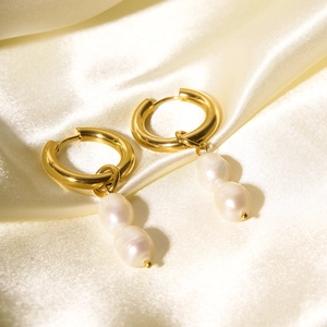 Detailed close-up of gold pearl earrings on elegant silk background with soft drapes
