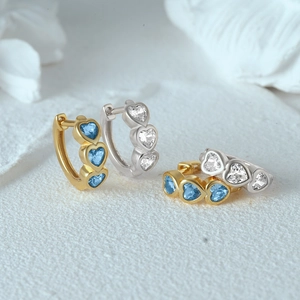 Detail of silver and gold heart earrings with blue and clear crystal gemstones