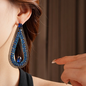 Close-up of teardrop earrings with blue crystals on model for a glamorous style