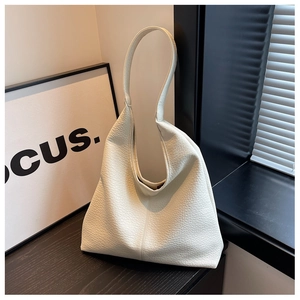 Close-up of cream leather tote bag with lychee texture on dark wood desk