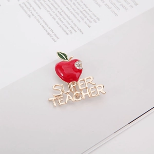 Broche pomme pour enseignant avec émail rouge et strass sur un livre blanc
