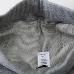 Détail de la taille d'un pantalon en maille gris avec bord-côte et étiquette taille 4 ans