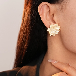 Détail des boucles d'oreilles en forme de fleur blanc crème sur un modèle féminin