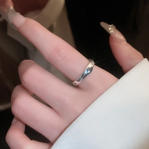 Close-up of minimalist silver wave ring with zircons worn by a model in warm light