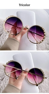 Detail of round gold sunglasses with pearl embellishments and purple gradient lenses
