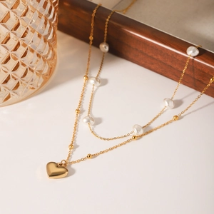 Double-layered gold heart pendant pearl necklace on a minimalist home decor background