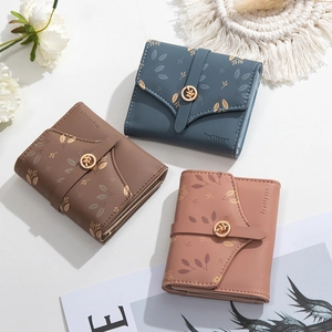 Detailed view of three-fold wallets with leaf print and golden metal leaf buckle