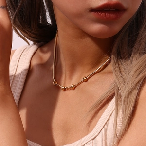 Detailed view of fashion gold-plated snake chain necklace with beads on female model