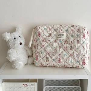 Quilted floral makeup bag with pink bunny and bear patterns on a white shelf
